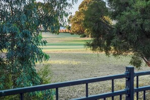 A view of a golf course with trees and a fence.