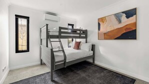 A bunk bed room with a ladder, a window, an air conditioning unit, and a painting on the wall. - Ember & Aqua—Luxury Barnhouse on the Golf Course (Dunsborough)