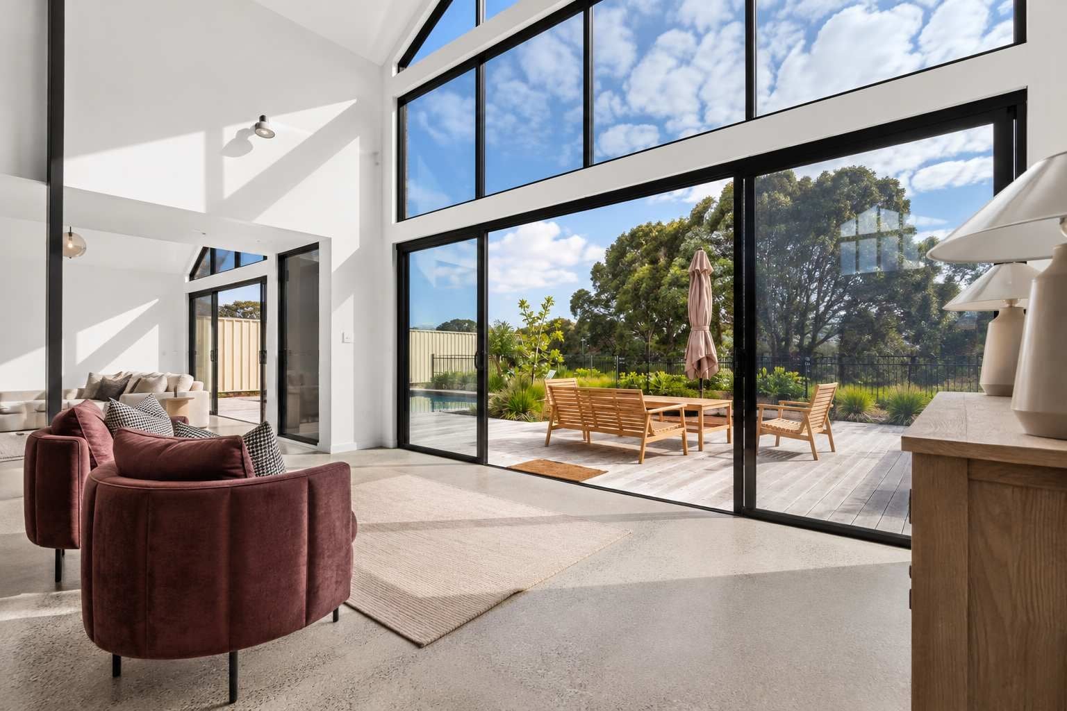A spacious living area with a large sliding glass door leading to an outdoor patio with furniture.
