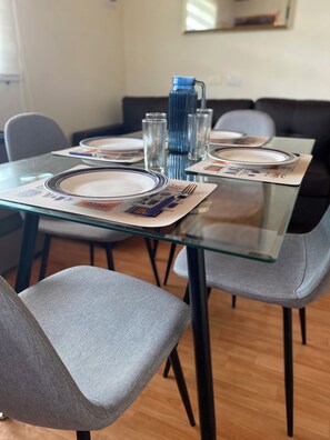 A dining area with a glass table, grey upholstered chairs, and a blue water bottle. - House in a natural setting (Curico)