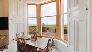 Ein Essbereich mit Erkerfenster, Holztisch, Stühlen und Blick ins Freie.