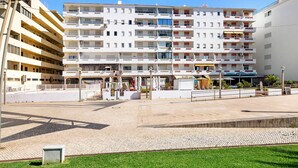A multi-story hotel with balconies, a paved courtyard, and a restaurant. - 'Paraná' Apartment with Balcony, Wi-Fi, and Air Conditioning (Quarteira)
