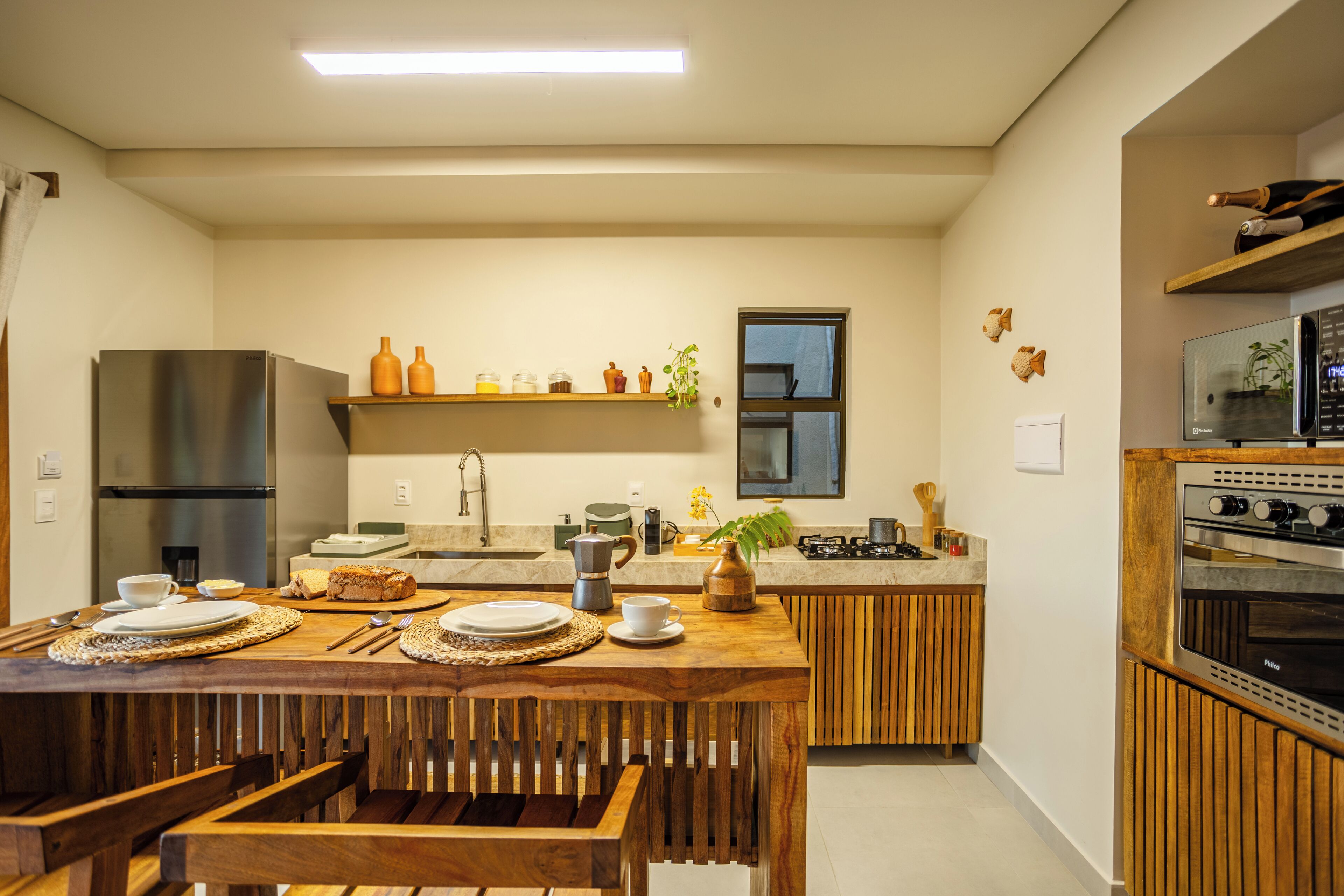 Een moderne keuken met een houten eettafel, roestvrijstalen apparatuur en een inbouwoven.