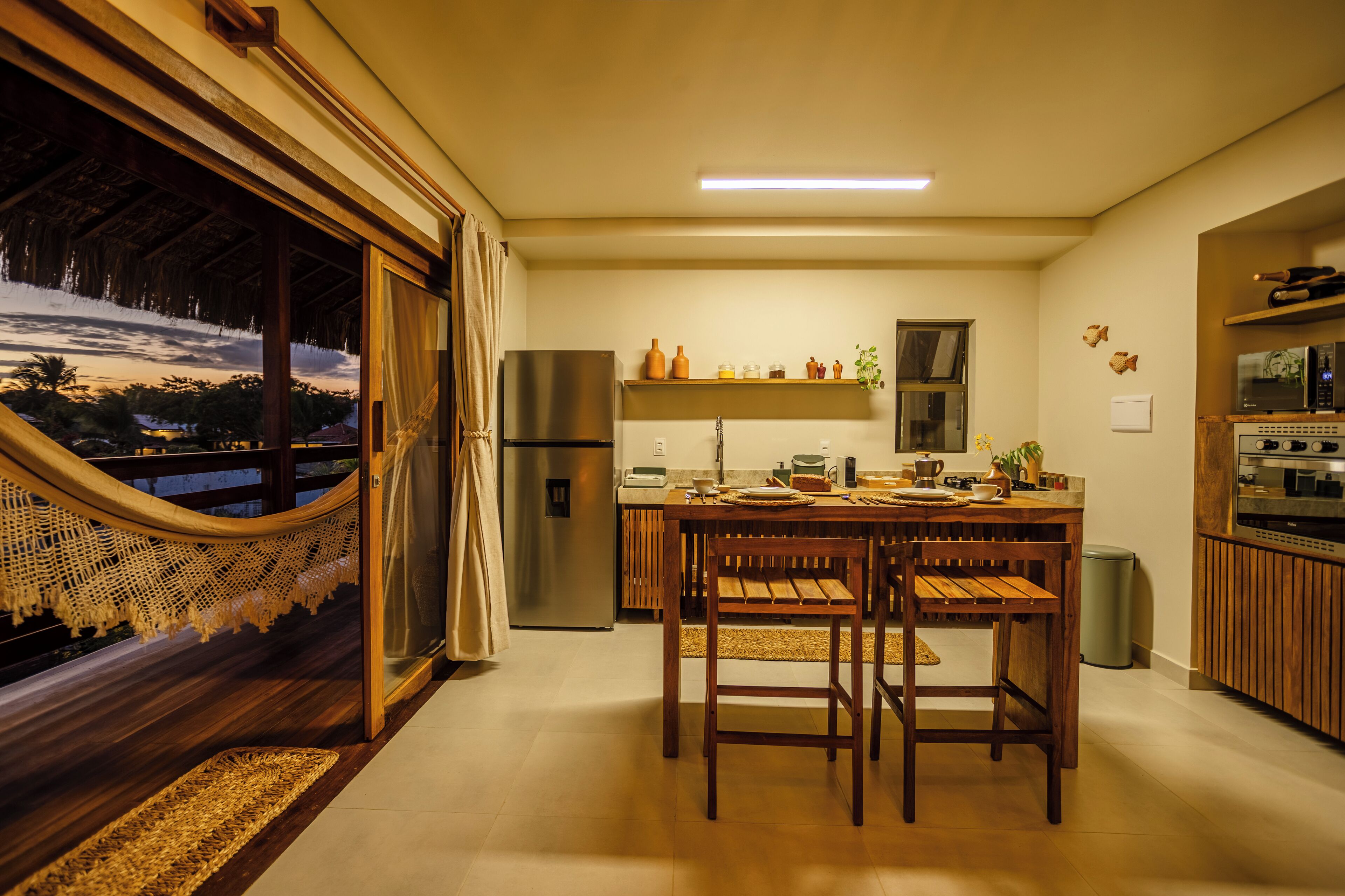 A modern kitchen with a dining area, a refrigerator, a microwave, and a view of the outdoors.