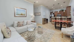 A modern living room with a sofa, coffee table, and a dining area with a table and chairs. - 2 Bed 2 Bath 2nd Fl Condo by Beach with Pool (South Padre Island)