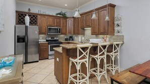 A kitchen with wooden cabinets, a stainless steel refrigerator, a microwave, and a granite countertop. - 2 Bed 2 Bath 2nd Fl Condo by Beach with Pool (South Padre Island)