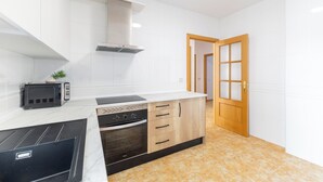 Een moderne keuken met witte tegels, een inbouwoven, een magnetron en een houten kast.