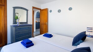 Une chambre à coucher comprenant un lit, une commode, un miroir et une porte donnant sur une salle de bain.