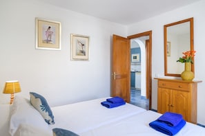 Una camera d'albergo con un letto, un armadio in legno, uno specchio e due quadri appesi al muro.