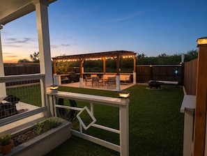 A backyard patio with a pergola, outdoor seating, and a barbecue area.
