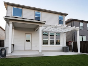 A two-story house with a covered patio, a front door, and a visible air conditioning unit. - Light and Airy 4-bedroom home in New Braunfels (New Braunfels)