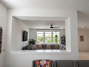 A living room with a sofa, a television, and a ceiling fan.