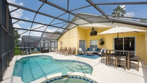 Ein Poolbereich mit Glasveranda, Liegestühlen und einem Esstisch mit Stühlen.