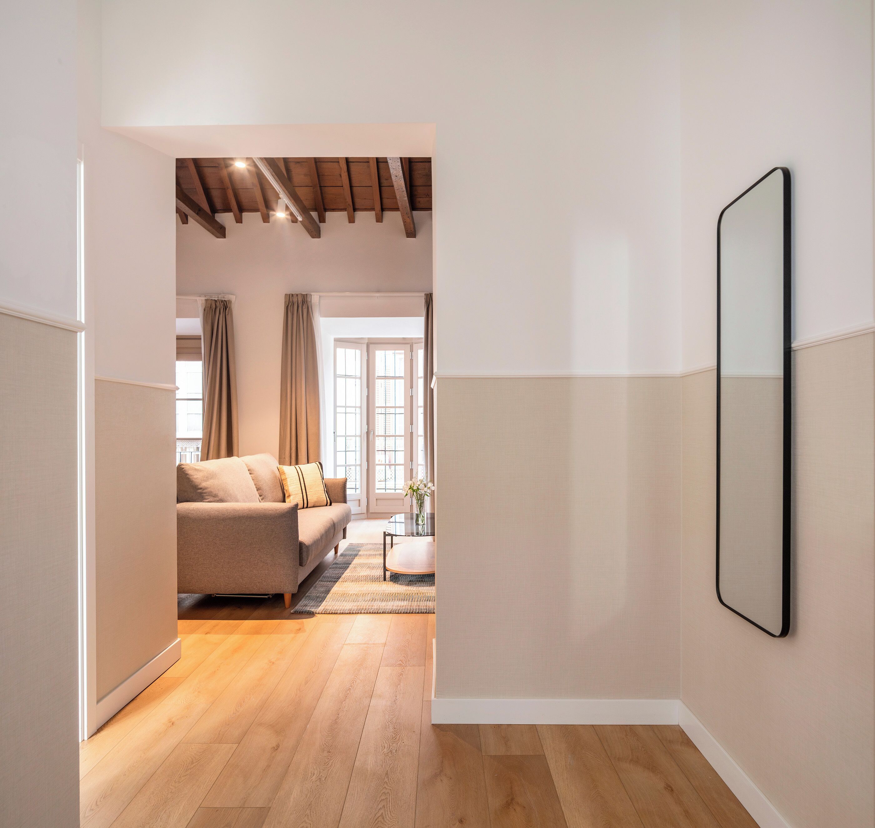 Un salon moderne avec un canapé, une table basse en verre et un plancher en bois.