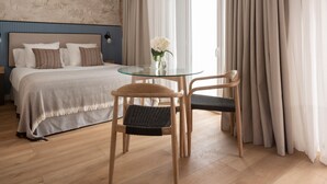 A bedroom with a bed, a glass table, two chairs, and a window with curtains. - Feelathome Palacio de Álamos (Distrito Centro)