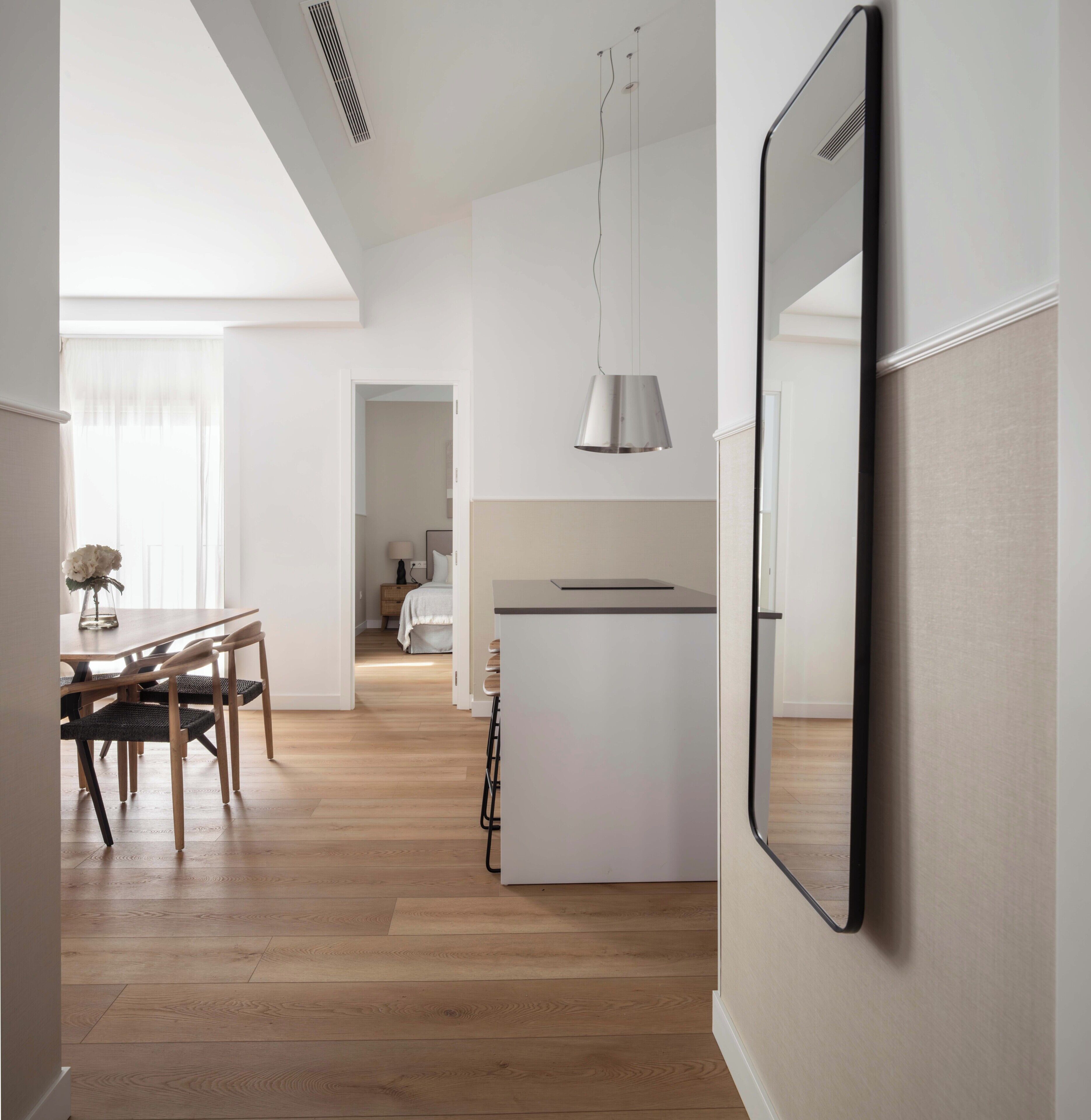Une cuisine moderne avec un îlot central, un plancher en bois et un luminaire suspendu.