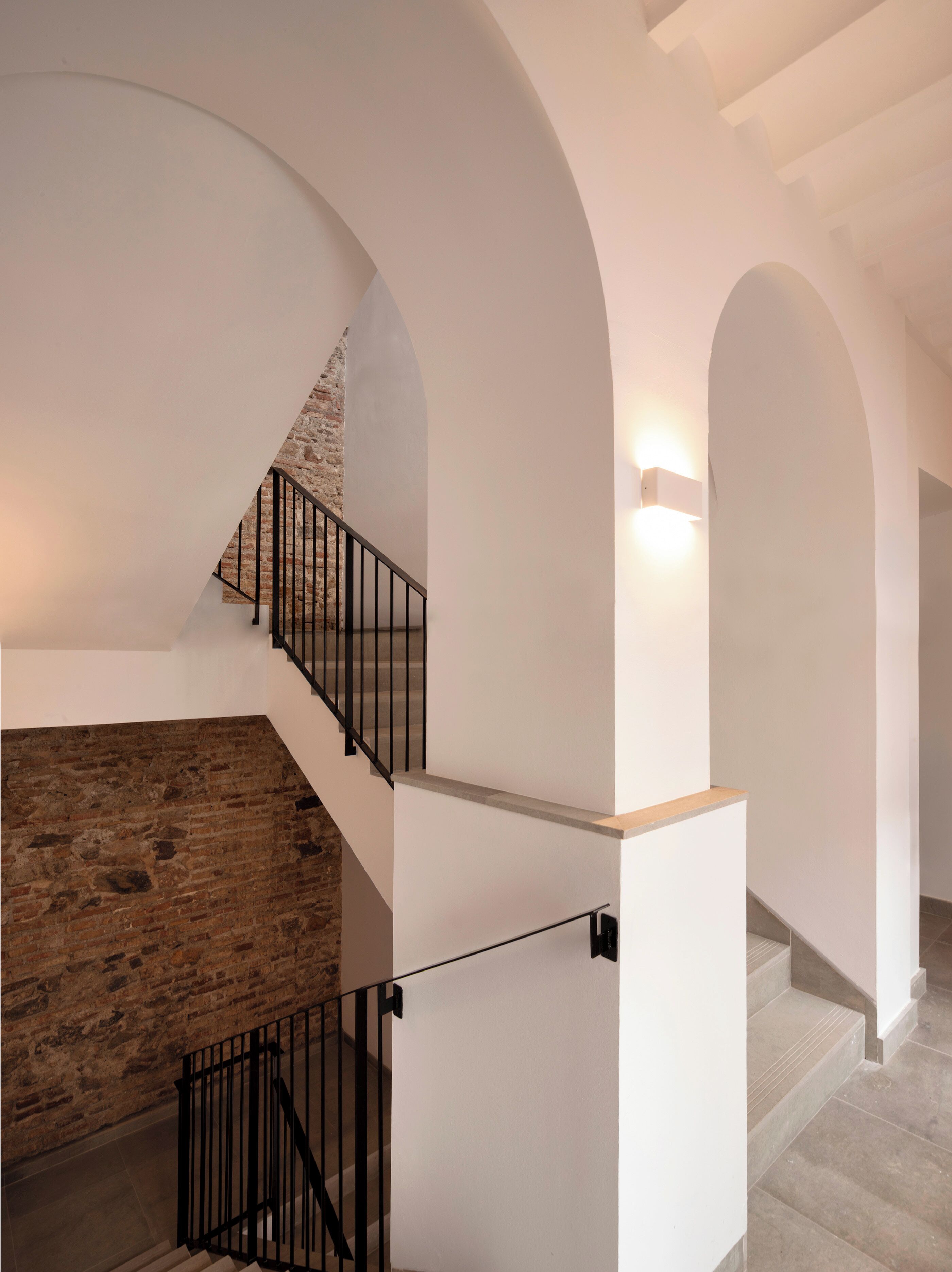 A staircase with a stone wall on one side and a white wall on the other, leading to an upper level.
