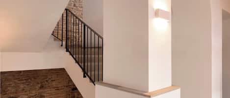 A staircase with a stone wall on one side and a white wall on the other, leading to an upper level.