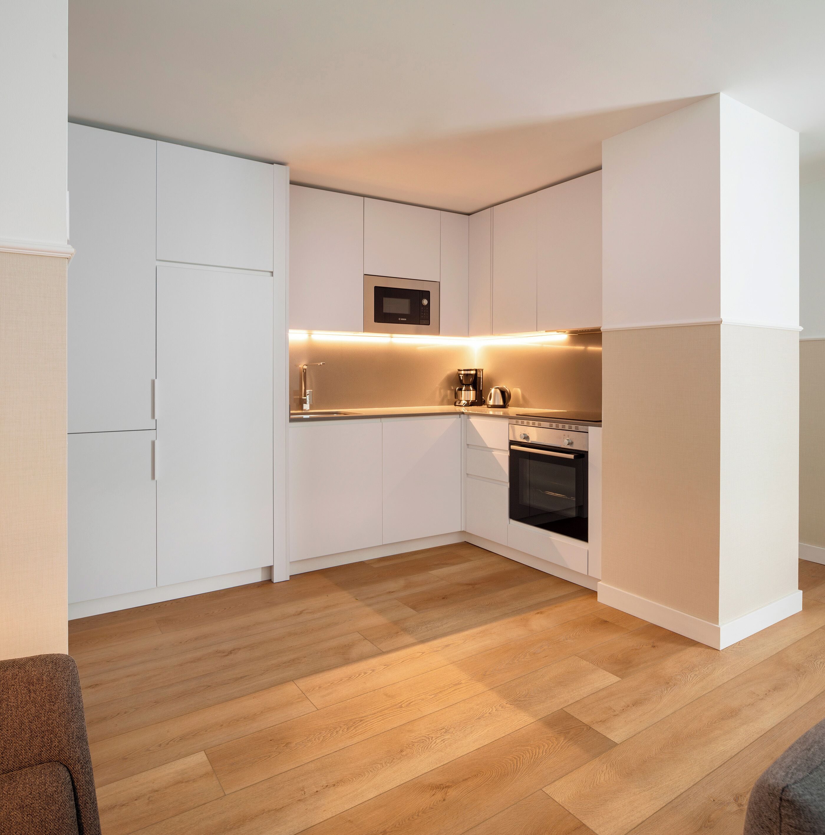 A modern kitchen with white cabinetry, a built-in oven, and a microwave.
