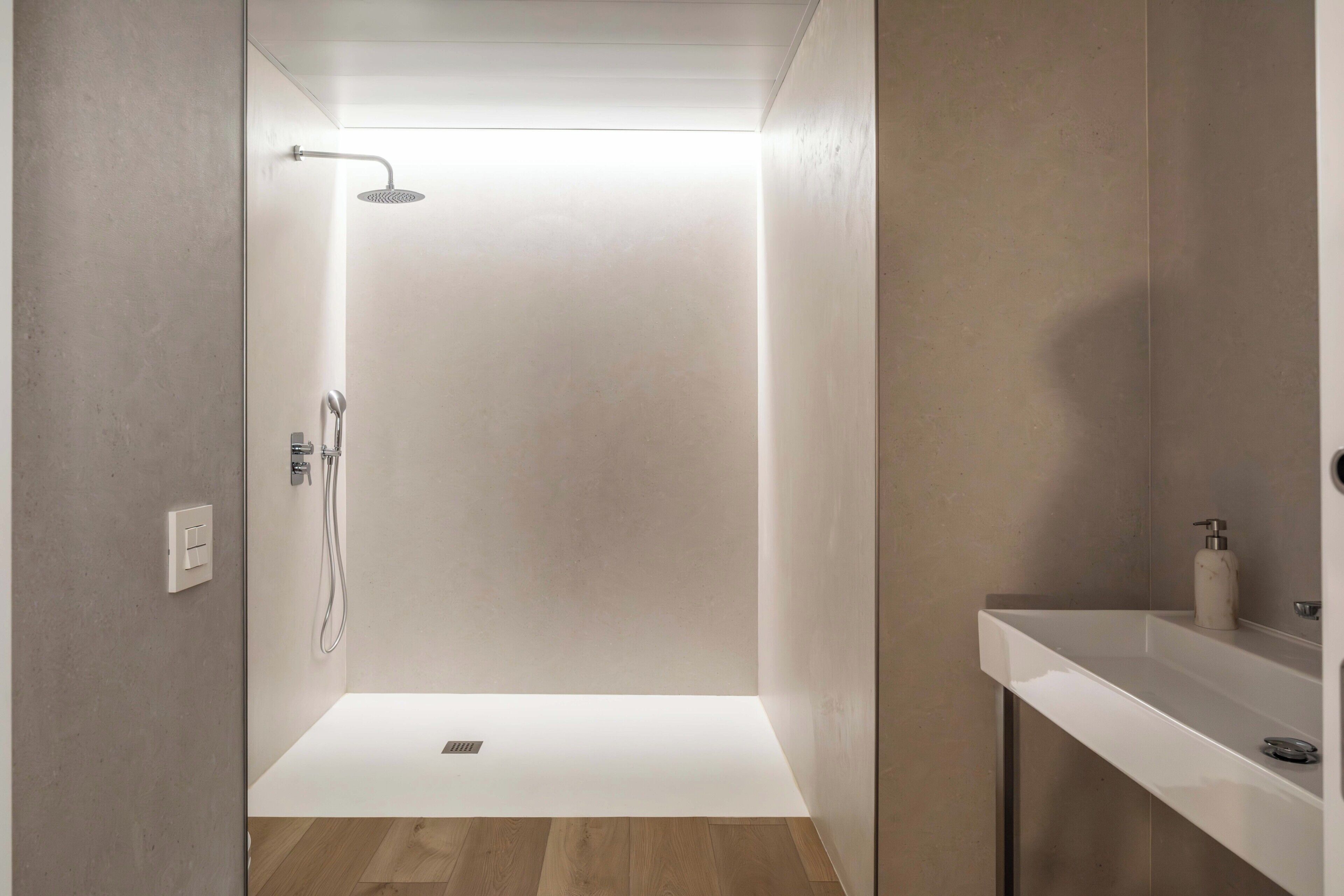 A modern shower area with a glass door, a handheld showerhead, and a wall-mounted faucet.