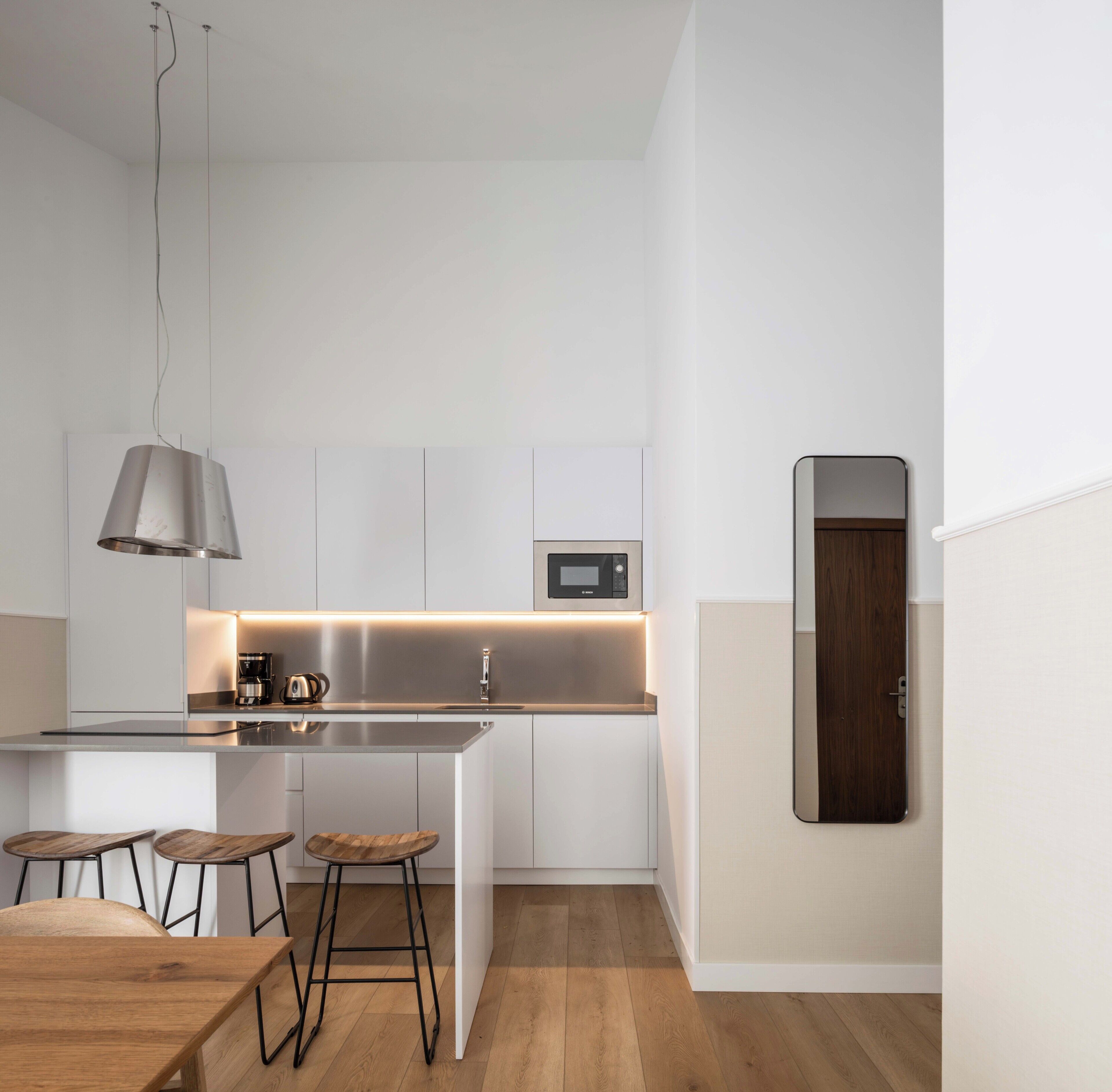 Une cuisine moderne dotée d’un îlot central, de tabourets de bar, d’un luminaire suspendu et d’un four à micro-ondes.