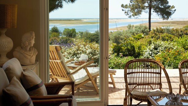 A room with a view of a beach and garden, furnished with wicker chairs and a table. - Luxury Oceanfront Villa - Catered & Serviced with Private Boat & Skipper (Tavira)