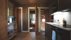 Een houten interieur met een keukenhoek, inclusief een koffiezetapparaat, een spoelbak en een aanrecht met flessen.