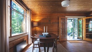 Een houten interieur met een ronde tafel, stoelen en een lamp.