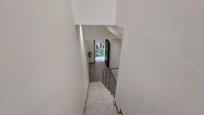 A staircase leading to a landing with a fire extinguisher mounted on the wall. - Zefiro Rooms (Agrigento)