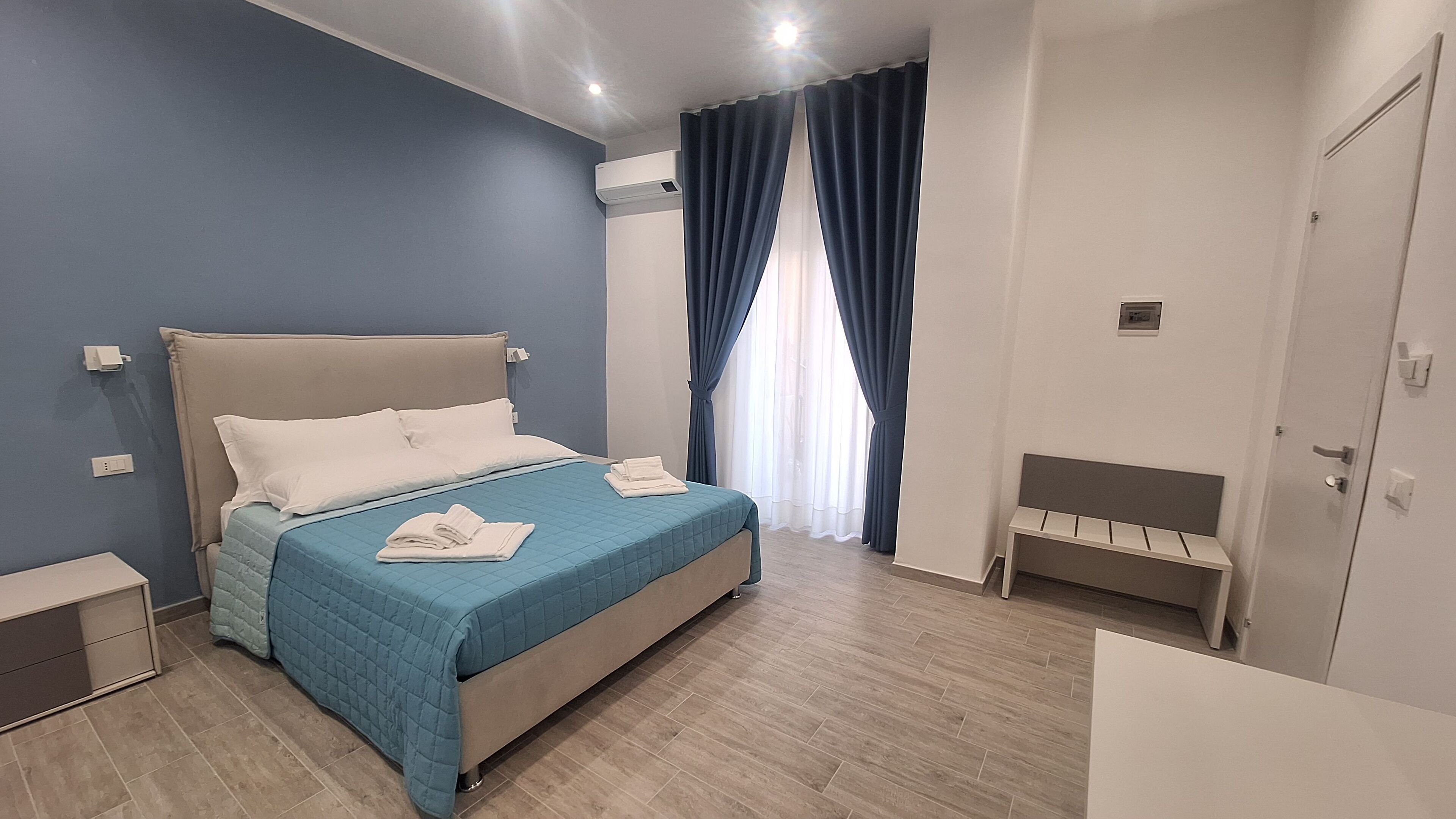 Une chambre à coucher moderne avec un lit, des tables de chevet et un banc.