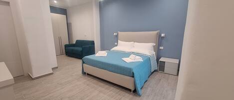 A modern bedroom with a bed, a blue sofa, and a wardrobe.