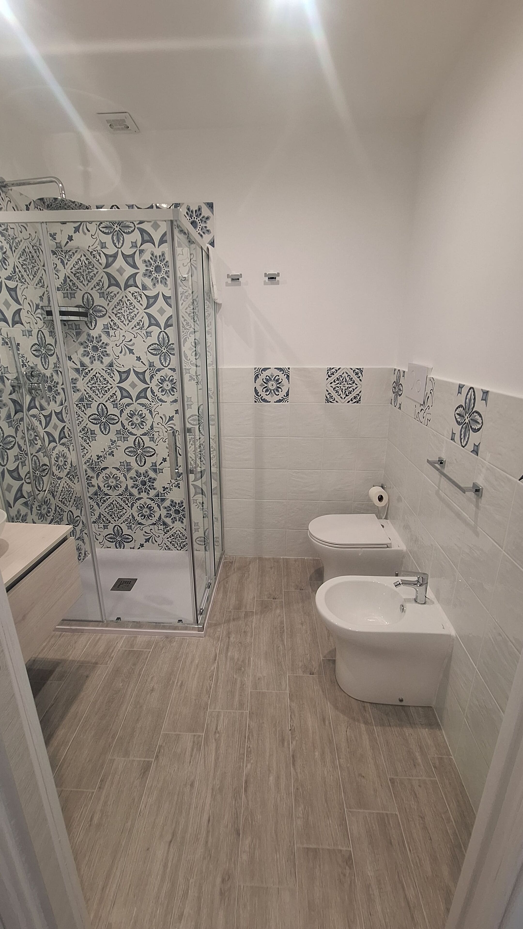 A modern bathroom with a shower enclosure, two bidets, and a toilet.