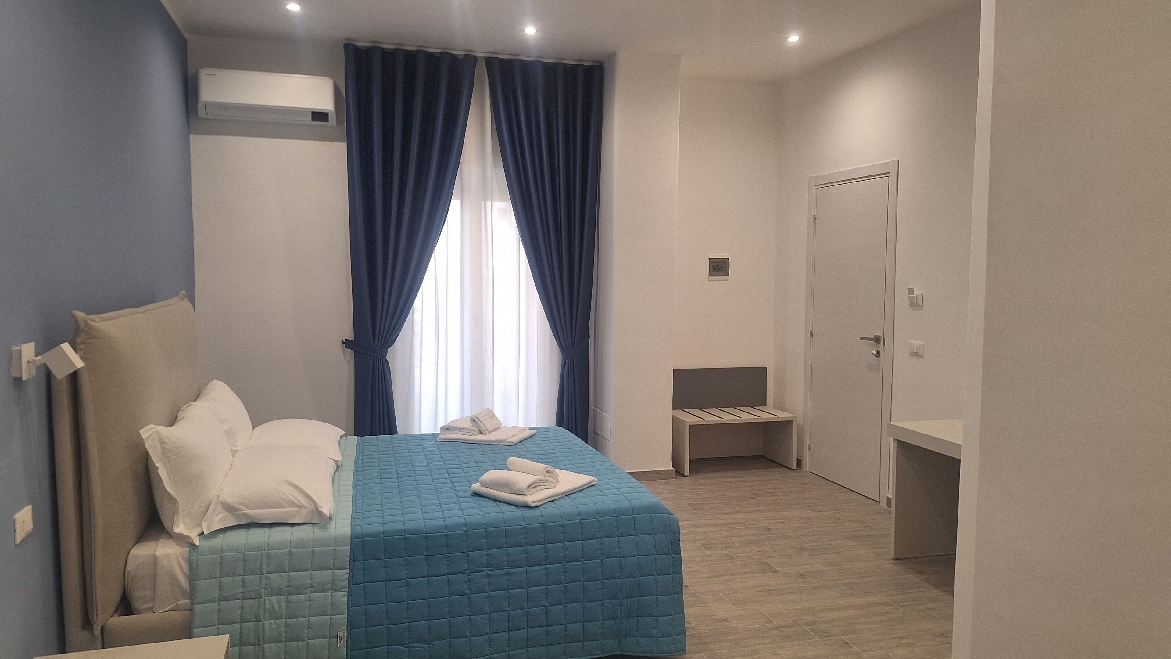 Une chambre à coucher comprenant un lit, une table de chevet, une armoire et une fenêtre avec des rideaux.