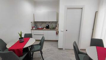 Um espaço compacto com área de refeições, cozinha compacta e porta que dá para outro cômodo.