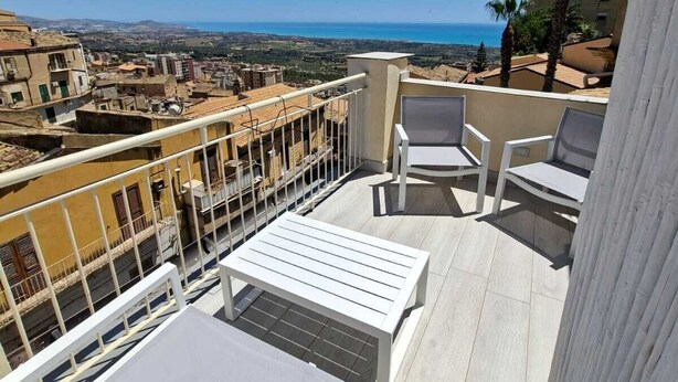 A balcony with a view of the sea, white furniture, and a railing. - Zefiro Rooms (Agrigento)
