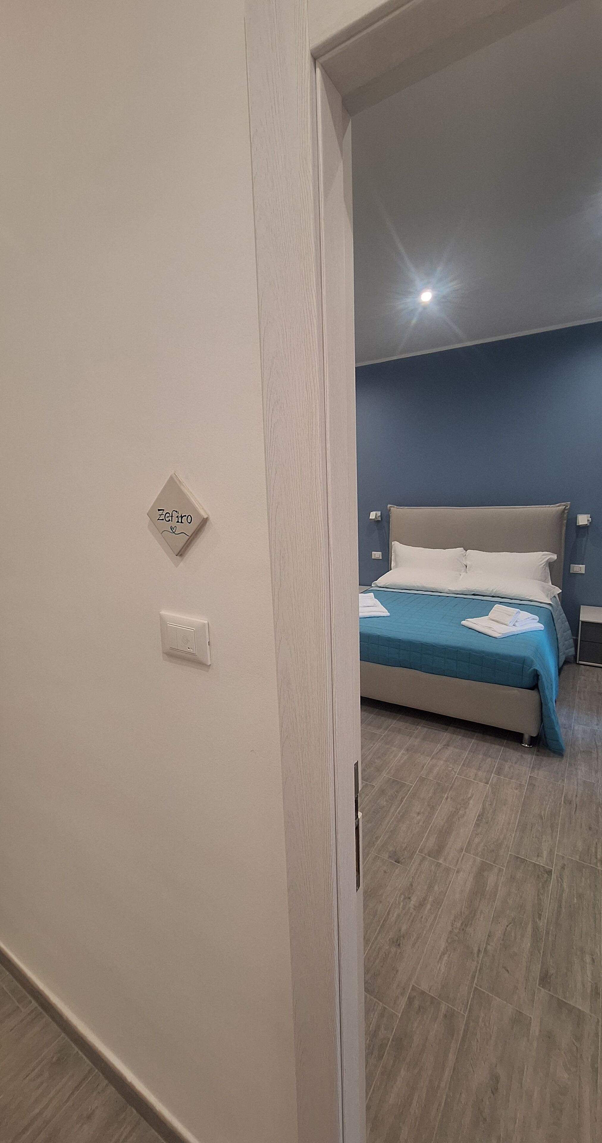 A bedroom with a bed, a nightstand, and a wall-mounted light switch.