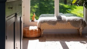 A room with a large sliding glass door leading to a garden, a wicker bench, and a hanging light fixture. - Stay North - Västerskog (Sipoo)