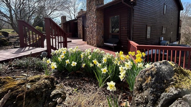 A rustic cabin with a stone chimney, a wooden deck, and a stone pathway leading to the entrance. - Private Cozy Studio (Radford)