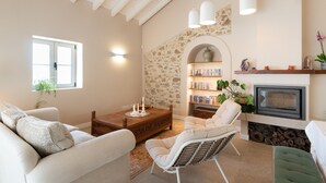 A living room with a fireplace, bookshelves, and a stone wall. - Holiday Home 'Modern Farmhouse with Pool' with Mountain View, Wi-Fi and Air Conditioning (Santo Estevão)