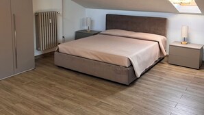 A bedroom with a sloped ceiling, a bed, a nightstand, a radiator, and a skylight. - Mia's House Dogliani - spacious, finely furnished studio apartment (Dogliani)