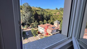 A window with a view of a residential area, including houses and greenery. - Mia's House Dogliani - spacious, finely furnished studio apartment (Dogliani)