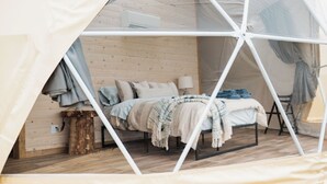 A tented room with a bed, wooden walls, and a window. - Salmon Bay Farm (Rivière-Saint-Paul)