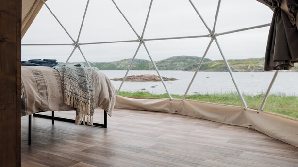 A tented room with a bed, a view of a lake, and a grassy area outside. - Salmon Bay Farm (Rivière-Saint-Paul)