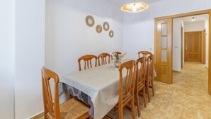 Un coin repas avec une table dressée pour six personnes, entourée de chaises en bois.