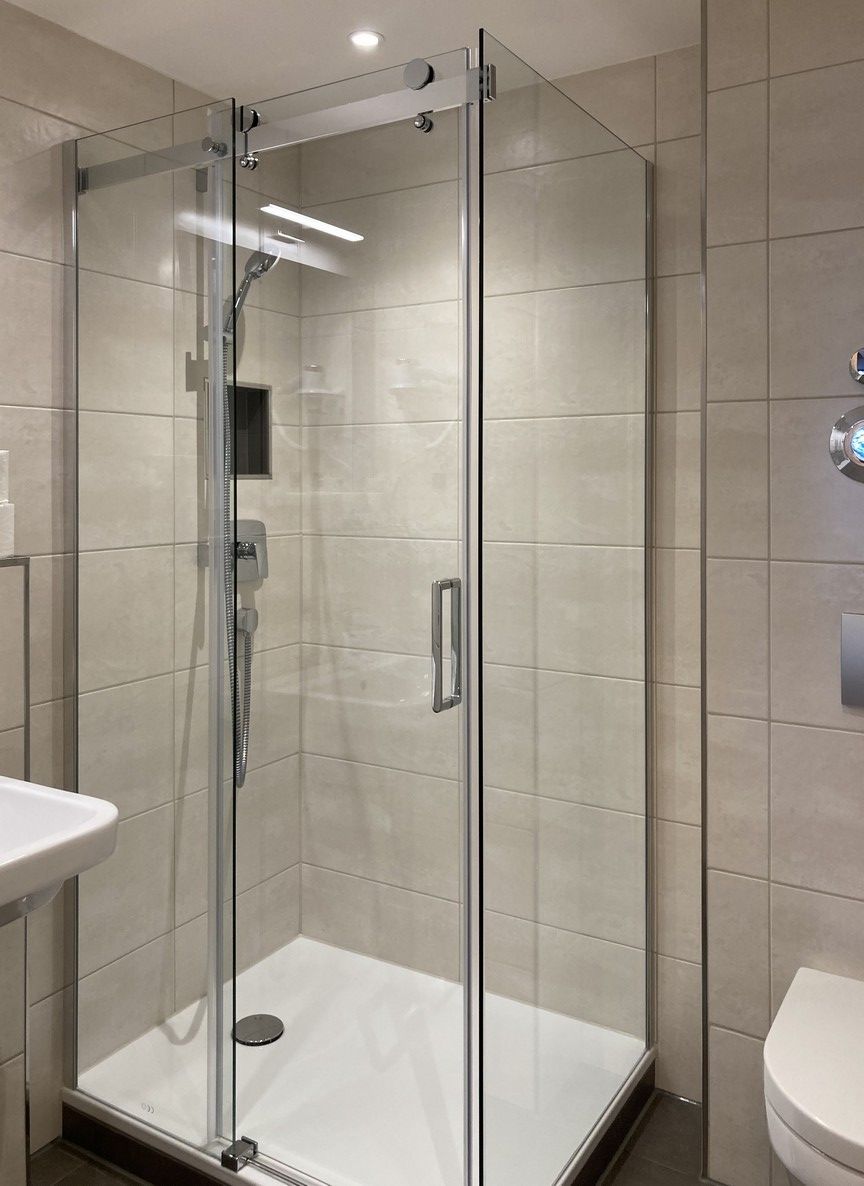 A modern bathroom with a glass-enclosed shower, a white sink, and a toilet.