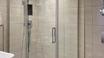 A modern bathroom with a glass-enclosed shower, a white sink, and a toilet.