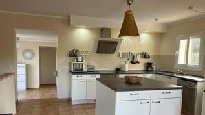 A modern kitchen with white cabinetry, a central island, and a hanging light fixture. - Has und Igel - Refuge in Cala Santanyi with Private Pool and Barbecue (Cala Santanyí)