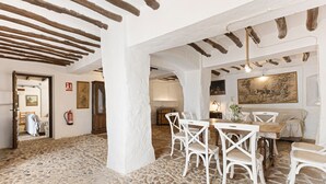 A room with a stone floor, white furniture, and exposed wooden beams. - Holiday Home 'Cortijo Caracate' with Mountain View, Wi-Fi and Air Conditioning (Archidona)