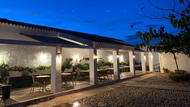 An outdoor patio area with tables and chairs, a covered walkway, and a view of the night sky. - Holiday Home 'Cortijo Caracate' with Mountain View, Wi-Fi and Air Conditioning (Archidona)