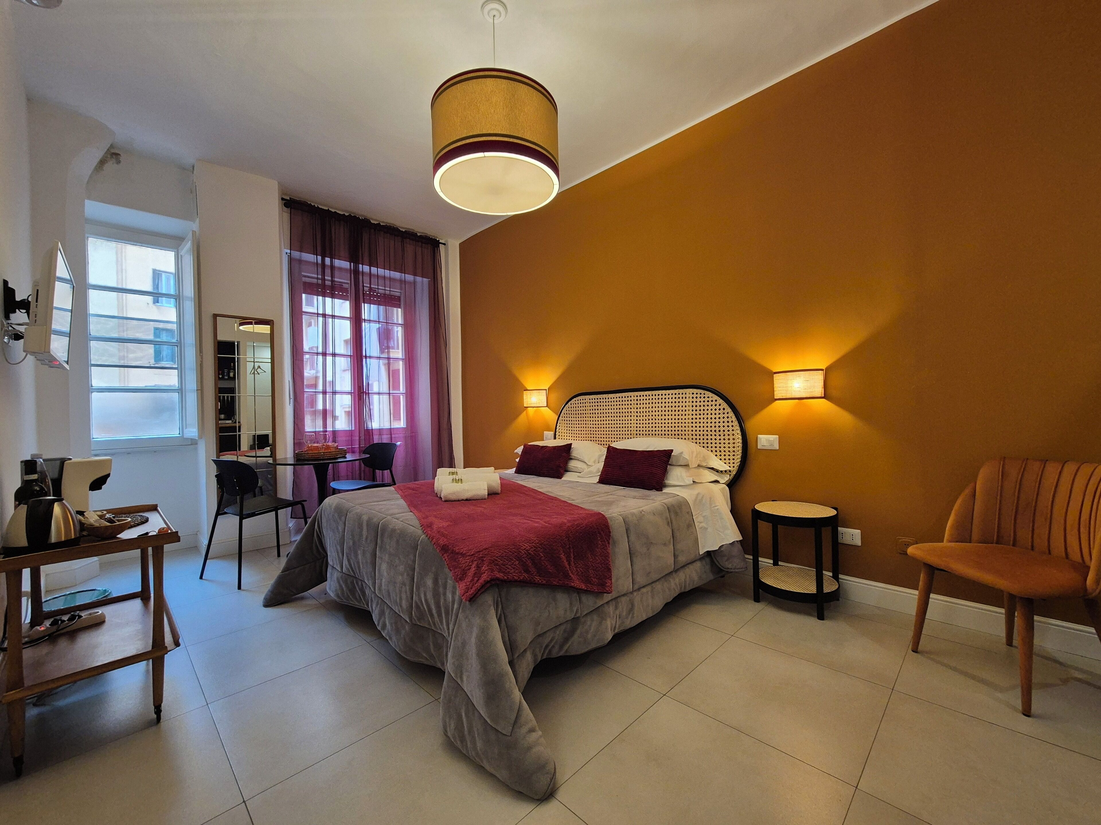 A bedroom with a large bed, a desk, a chair, and a small round table.